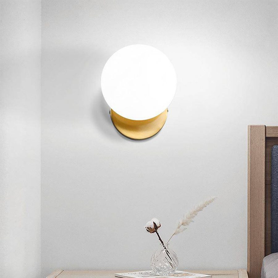 Lámpara de pared tipo apliqué dorado con una esfera de vidrio color blanco mate